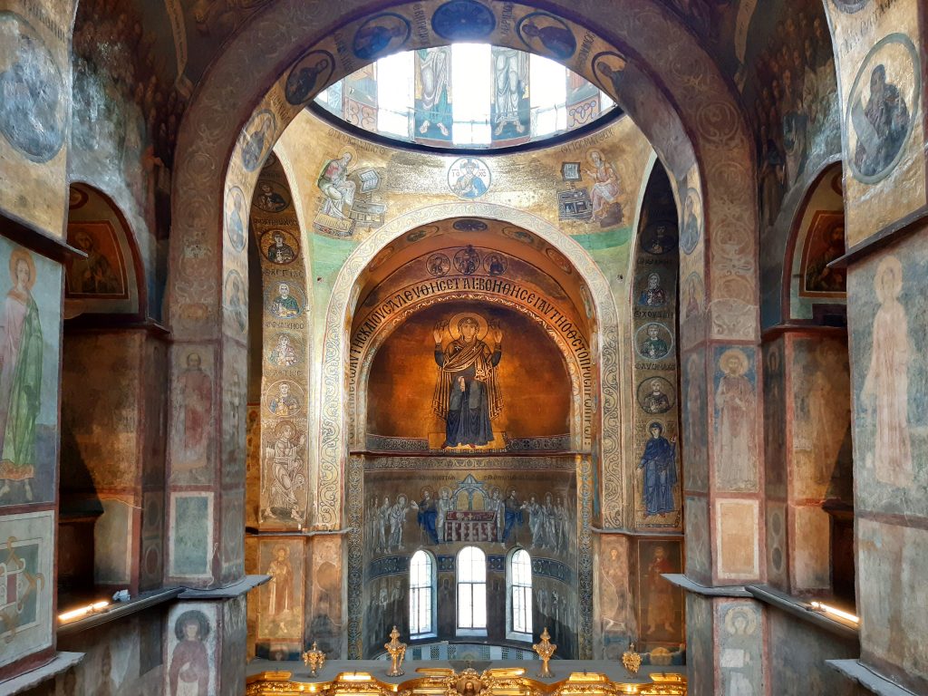 The interior of a domed church, its walls decorated with mosaics and paintings.