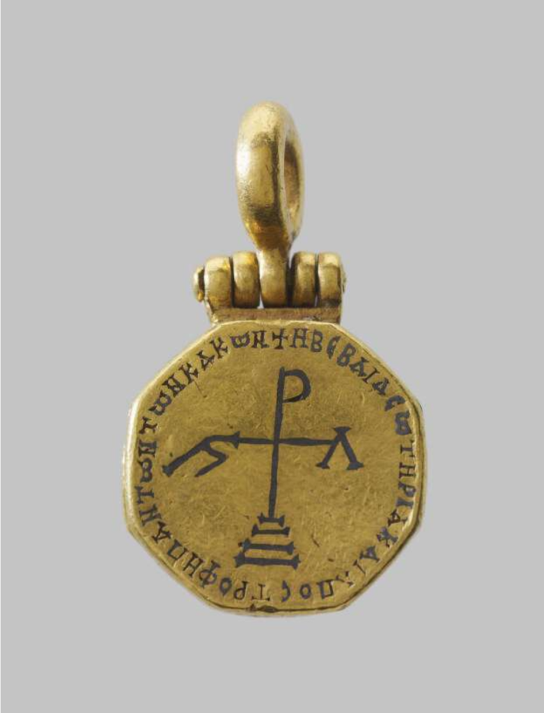 A gold pendant inscribed with a cross on steps and Greek lettering.