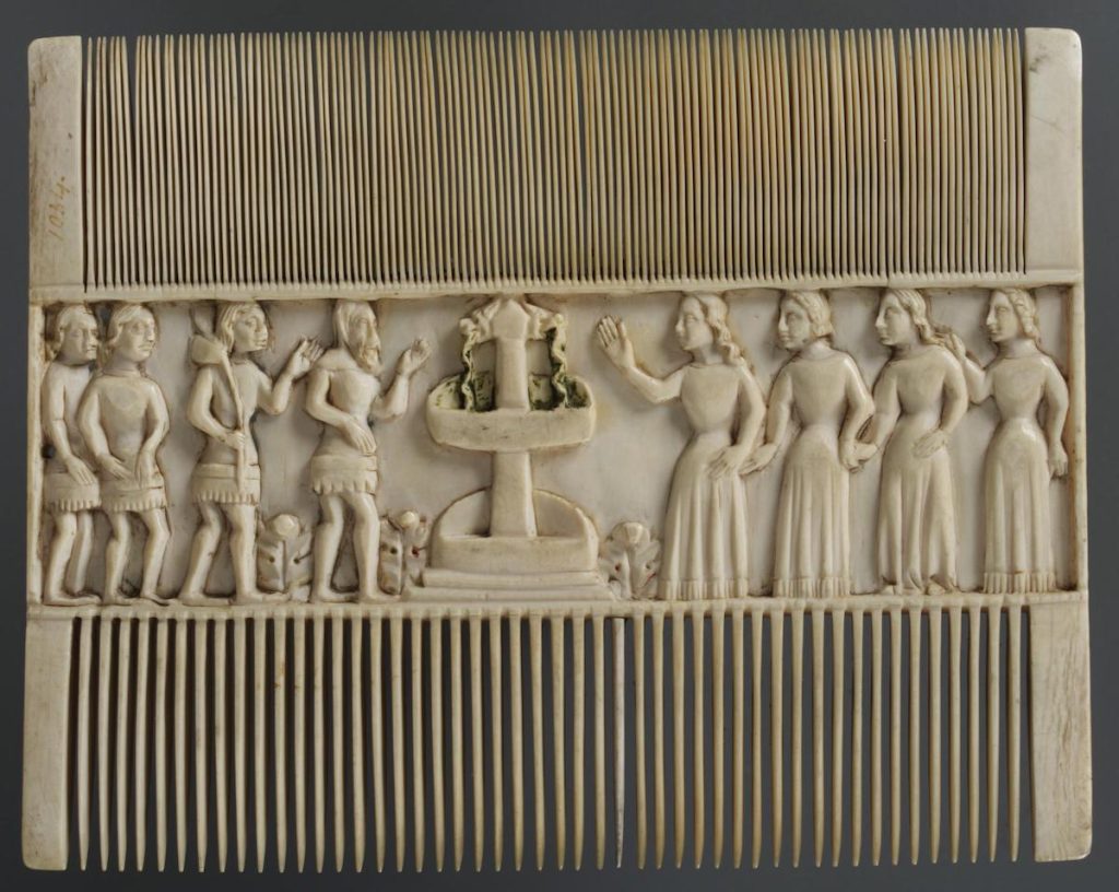 Carved ivory comb with wider teeth on bottom side and decorated in the middle with horizontal scene of four men and four woman, flanking fountain spouting water.
